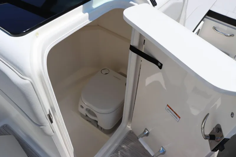 Slide: The Image of 2024 Sea Ray 230SPX boat interior with compact marine toilet. - 13