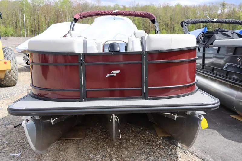 Slide: The Image of 2024 Starcraft EXS 3 pontoon boat with maroon exterior, parked on gravel. - 8