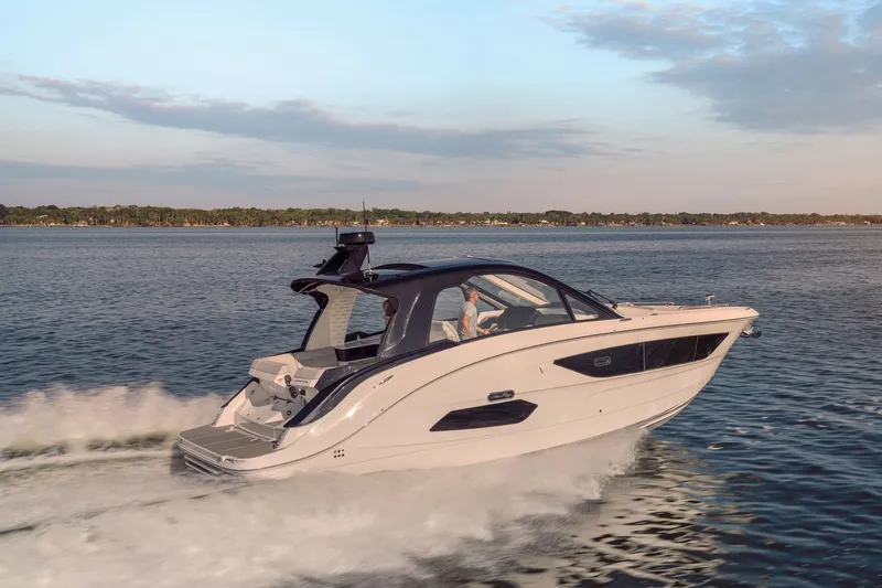 Slide: The Image of 2024 Sea Ray 370 Sundancer cruising on a serene lake at sunset. - 13