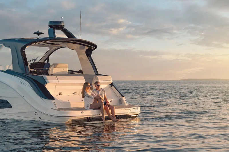 Slide: The Image of 2024 Sea Ray 370 Sundancer yacht on serene water at sunset with two people relaxing. - 17