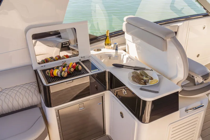 Slide: The Image of 2024 Sea Ray 370 Sundancer yacht with outdoor grill and dining setup. - 30