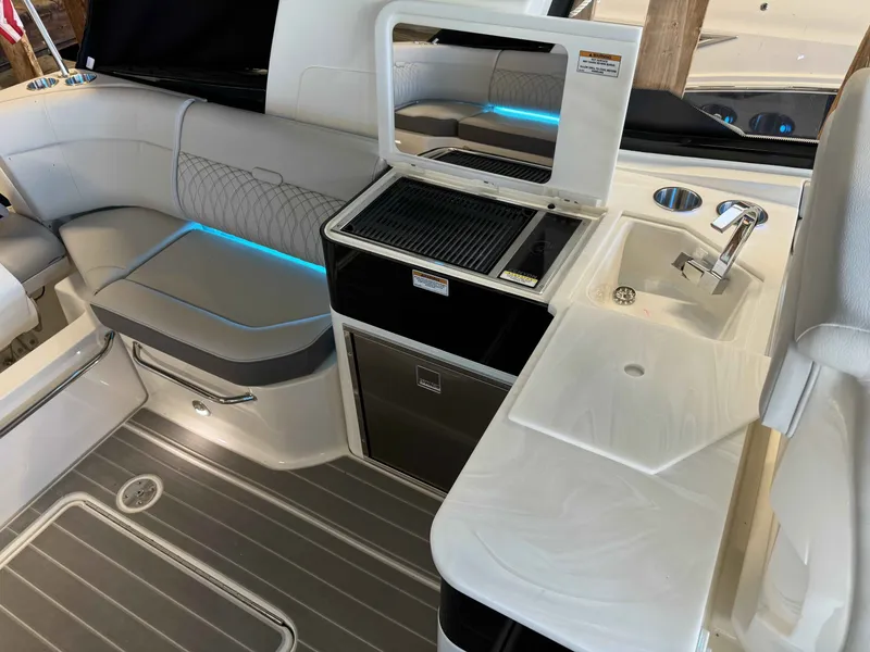Slide: The Image of 2024 Sea Ray 370 Sundancer interior with seating, sink, and grill area. - 7
