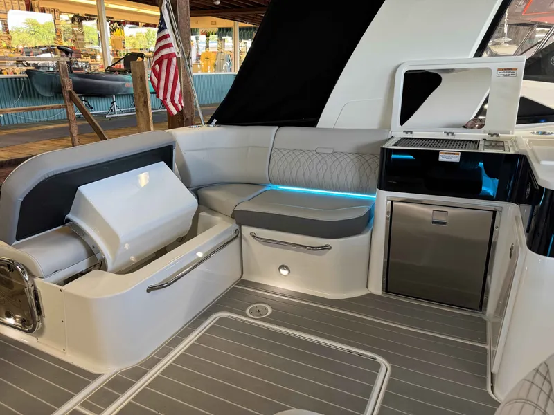 Slide: The Image of 2024 Sea Ray 370 Sundancer yacht interior with seating, kitchenette, and American flag. - 8