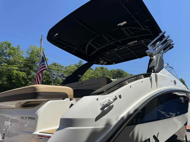 Slide: The Image of 2024 Sea Ray 260SXS boat with black canopy and American flag in the background. - 5