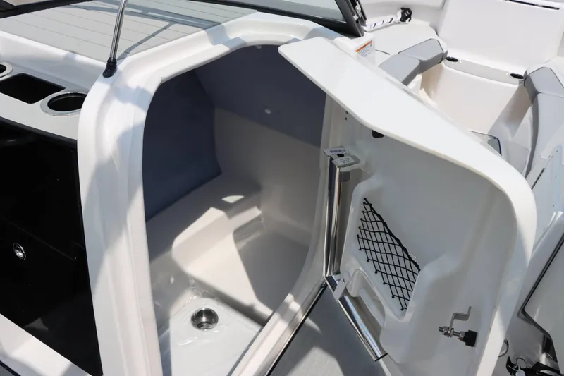 Slide: The Image of 2024 Yamaha AR250 boat interior storage compartment with open door and cup holders. - 23