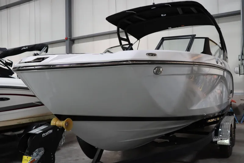 Slide: The Image of 2024 Yamaha Boats 222SD in showroom, sleek white design, on trailer. - 2