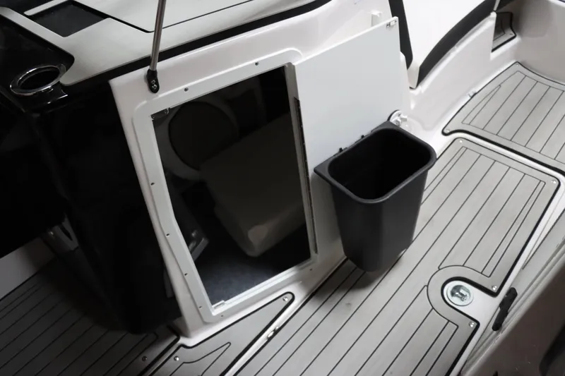 Slide: The Image of 2024 Yamaha Boats 222SD interior storage compartment with trash bin on deck. - 21