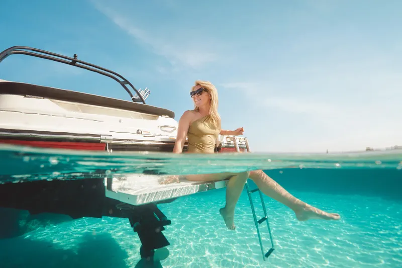 Slide: The Image of Woman relaxing on a 2024 Sea Ray 210SPX boat in clear blue water. - 19