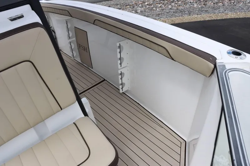 Slide: The Image of Interior of 2023 Yamaha Boats 255FSH SPORT E, featuring beige seating and rod holders. - 15