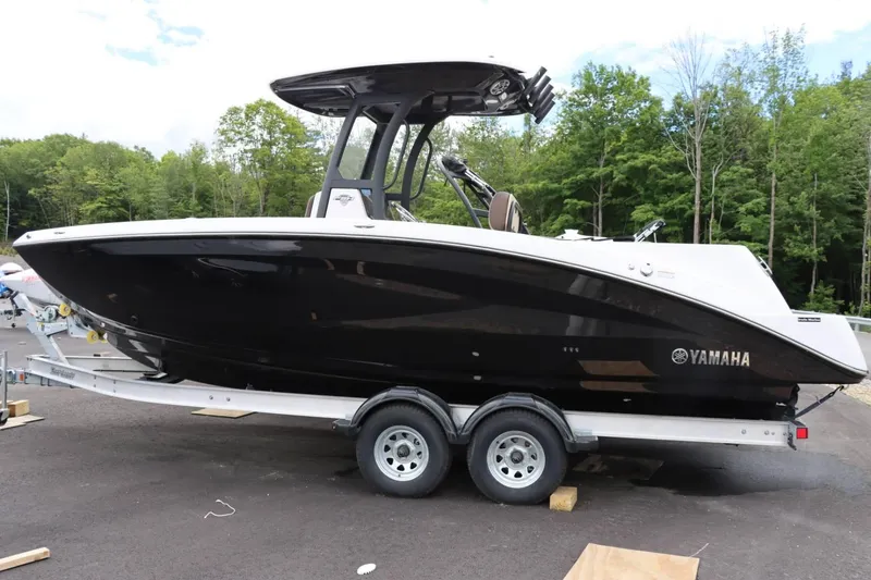 Slide: The Image of 2023 Yamaha Boats 255FSH SPORT E on trailer, black hull, outdoor setting. - 2