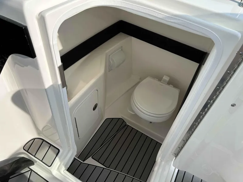 Slide: The Image of 2023 Sea Ray 260SXS boat interior with compact marine toilet and sleek flooring. - 6