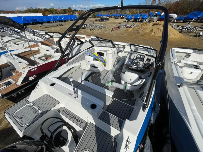 Slide: The Image of 2024 Starcraft SVX 190 OB boat interior with helm, seating, and deck in a marina. - 16