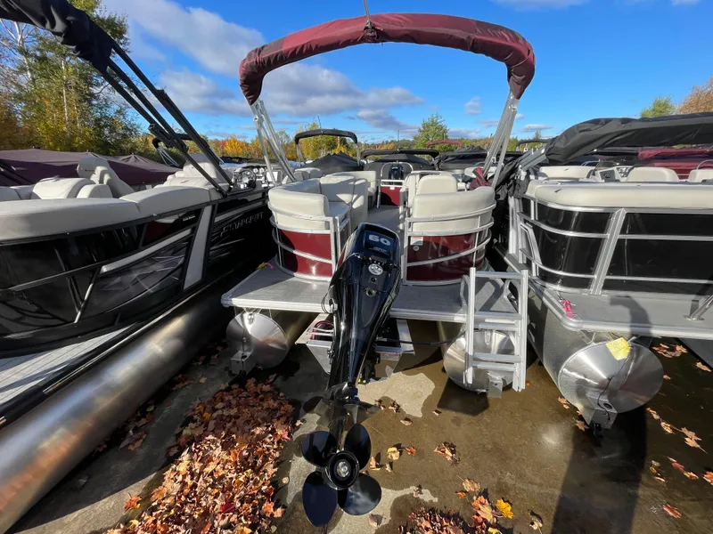 Slide: The Image of 2024 SunChaser VISTA 18LR pontoon boat with outboard motor, docked among other boats. - 9