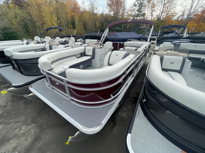 Slide: The Image of 2023 Starcraft EX 22C pontoon boat with white and maroon seating, docked in a marina. - 10