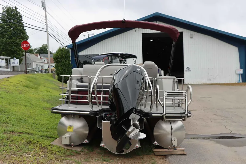 Slide: The Image of 2023 Starcraft CX 23Q DH pontoon boat with outboard motor, parked near a warehouse. - 5