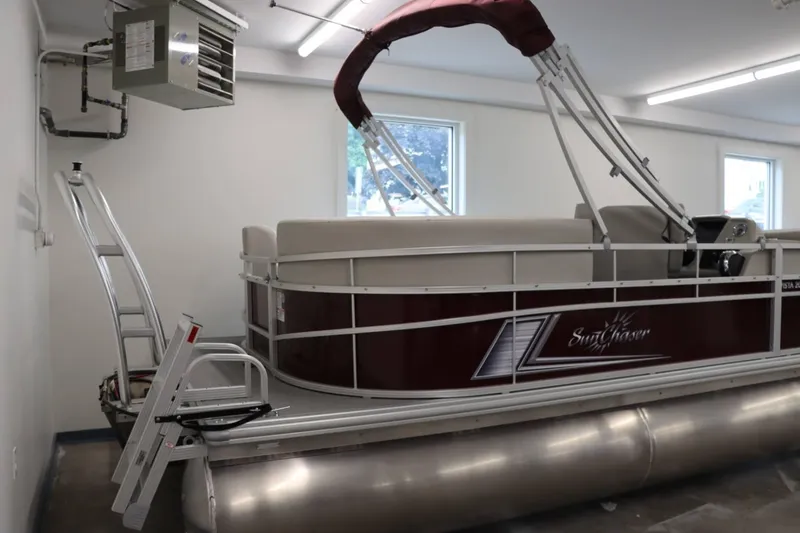 Slide: The Image of 2023 SunChaser VISTA 20LR pontoon boat stored indoors with maroon canopy. - 3