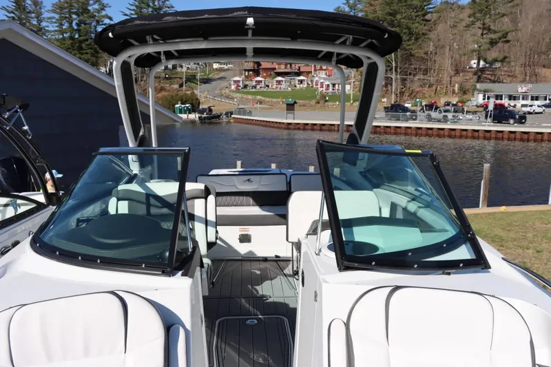 Slide: The Image of 2023 Monterey 298SS boat interior with open windshield, docked by a scenic lakeside. - 25
