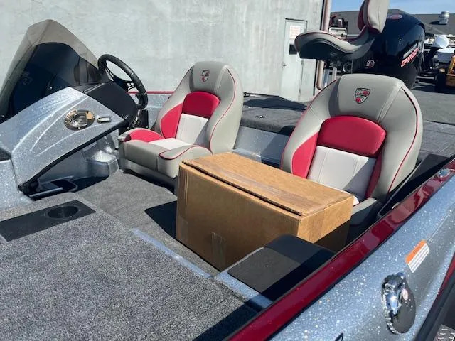 Slide: The Image of 2024 Triton 18 TrX boat interior with red and gray seats and a cardboard box. - 5