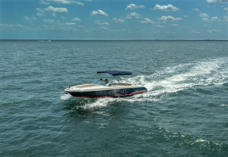 Slide: The Image of 2004 Chris-Craft Corsair 28 speedboat cruising on open water under a clear sky. - 14
