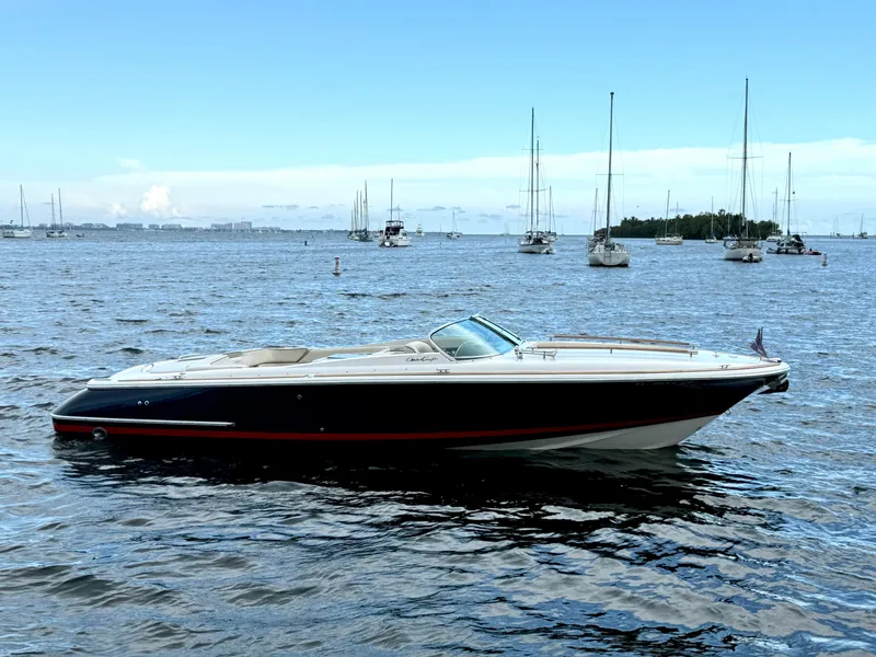 Slide: The Image of 2004 Chris-Craft Corsair 28 boat on calm waters with sailboats in the background. - 2