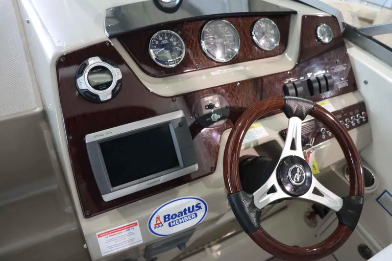 Slide: The Image of 2012 Sea Ray 280 Sundancer dashboard with steering wheel, gauges, and Garmin GPS. - 23