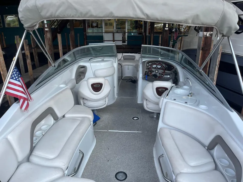 Slide: The Image of 2004 Crownline 270BR boat interior with seating, steering wheel, and American flag. - 4