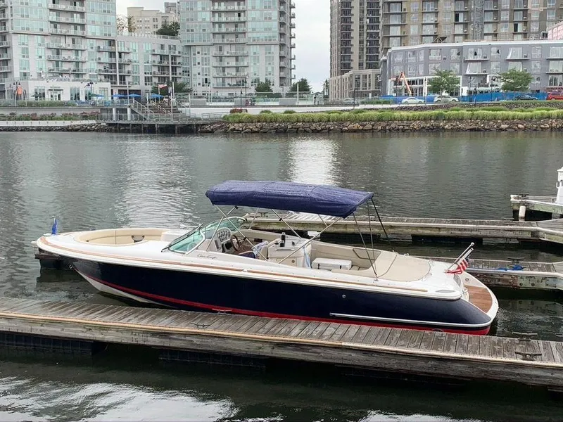 Slide: The Image of 2004 Chris-Craft 28 LAUNCH boat docked in a marina with cityscape background. - 1