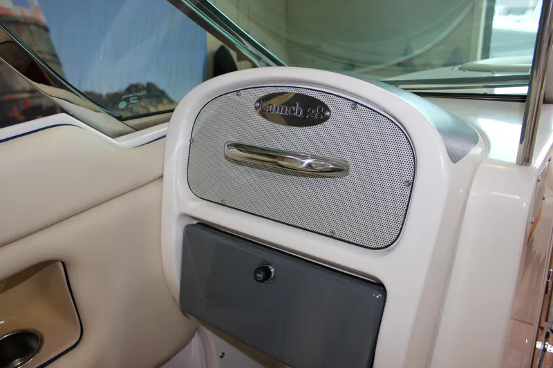 Slide: The Image of 2004 Chris-Craft 28 Launch boat interior, featuring dashboard and storage compartment. - 28