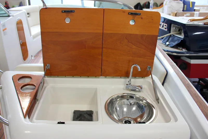Slide: The Image of 2004 Chris-Craft 28 Launch boat sink and counter with wooden cover and cup holders. - 34