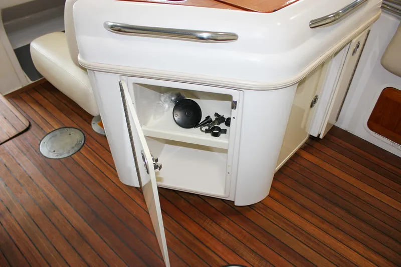 Slide: The Image of 2004 Chris-Craft 28 Launch interior with open storage cabinet and wooden flooring. - 35