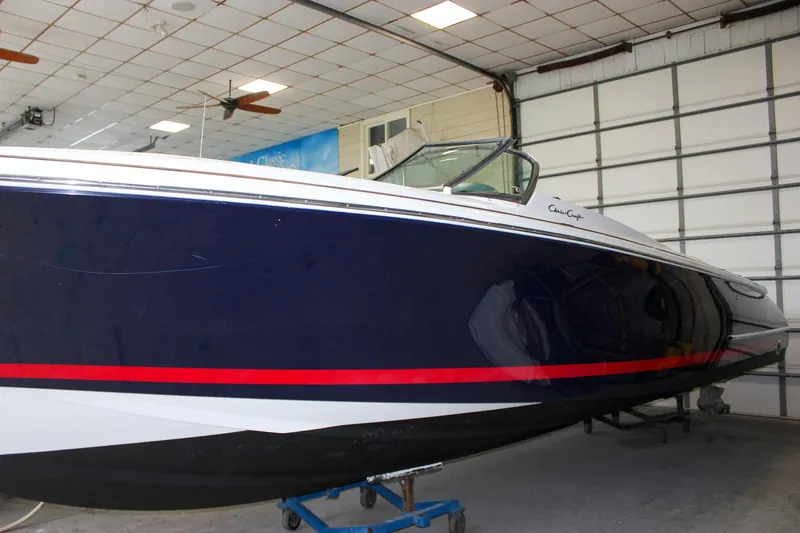 Slide: The Image of 2004 Chris-Craft 28 Launch boat in a garage, featuring a sleek navy and red design. - 46