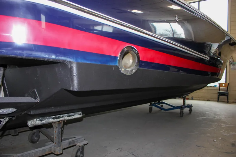 Slide: The Image of 2004 Chris-Craft 28 LAUNCH boat hull with red and blue stripes in a workshop. - 51
