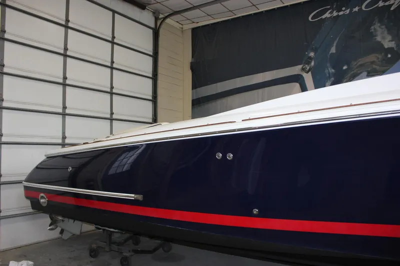 Slide: The Image of 2004 Chris-Craft 28 Launch boat in garage, featuring sleek navy and red design. - 9