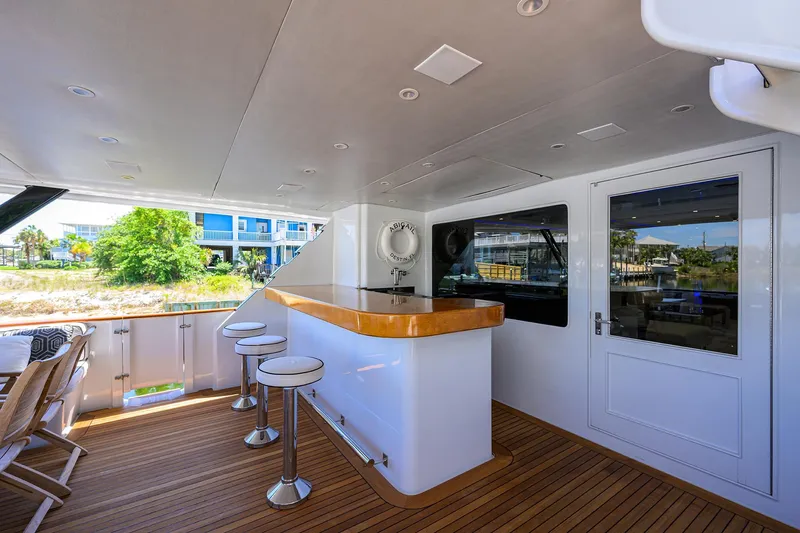 Slide: The Image of Outdoor bar area on 1997 Broward 108 Raised Pilothouse yacht with stools and wooden deck. - 10