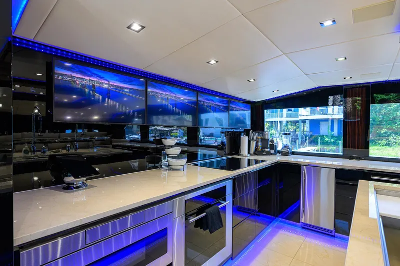 Slide: The Image of Luxurious kitchen interior of 1997 Broward 108 Raised Pilothouse yacht with modern appliances and blue LED lighting. - 34