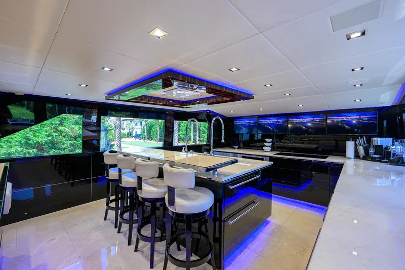 Slide: The Image of Luxurious interior of 1997 Broward 108 Raised Pilothouse yacht with modern kitchen and bar stools. - 35