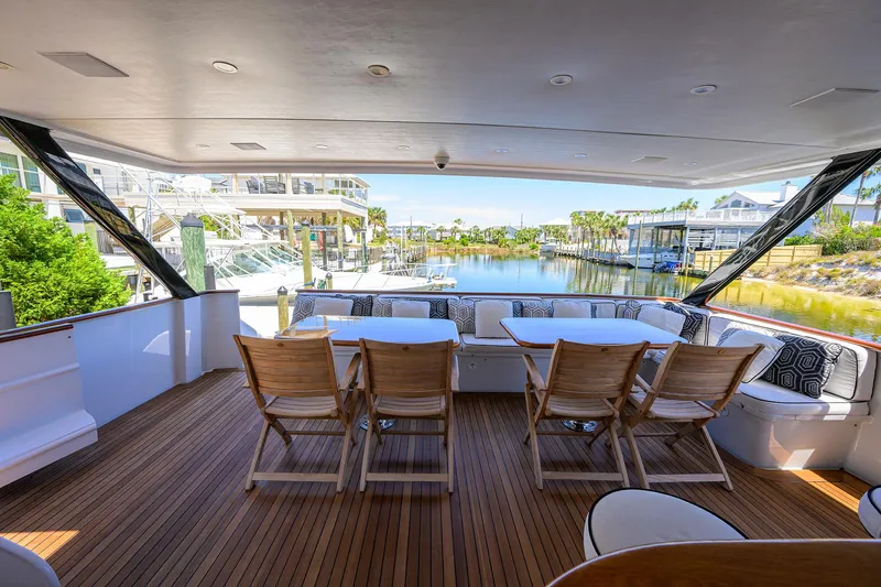 Slide: The Image of Spacious deck of 1997 Broward 108 Raised Pilothouse yacht with wooden chairs and waterfront view. - 6