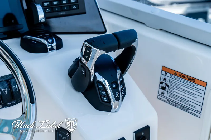 Slide: The Image of 2024 Sea Fox 288 Traveler Dual Console helm controls with warning label and steering wheel. - 21