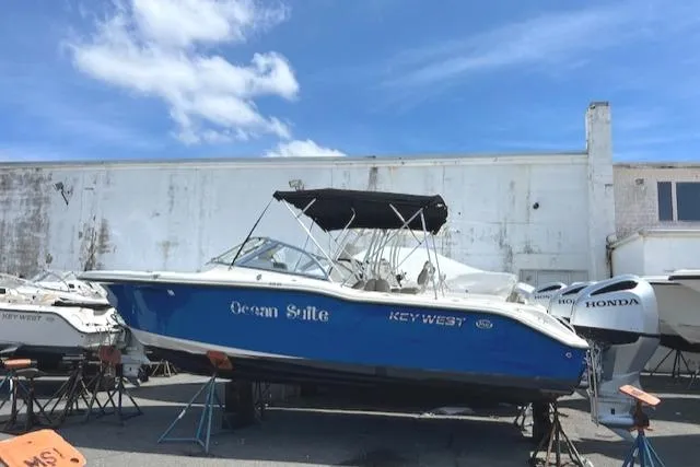 Slide: The Image of 2020 Key West 239 DFS boat in storage yard with blue hull and black canopy. - 2