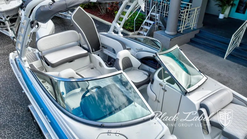 Slide: The Image of 2024 Crownline E260 XS boat interior with seating and windshield, docked near steps. - 7