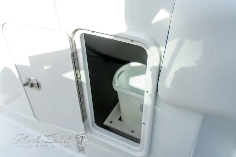 Slide: The Image of 2024 Crownline E260 XS storage compartment with a white container inside. - 16