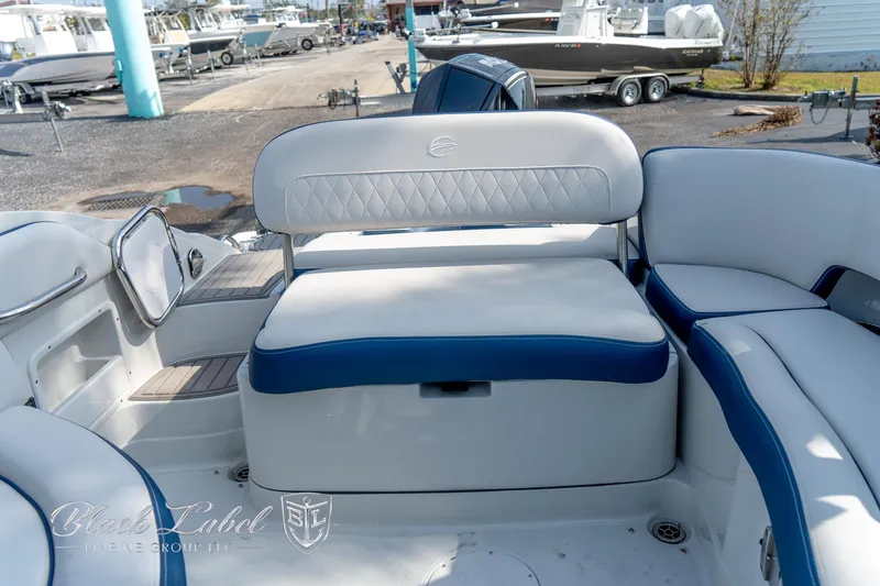 Slide: The Image of 2024 Crownline E260 XS boat interior with white and blue seating, docked at a marina. - 32