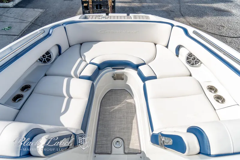 Slide: The Image of 2024 Crownline E260 XS boat interior with white and blue seating, featuring cup holders and speakers. - 7