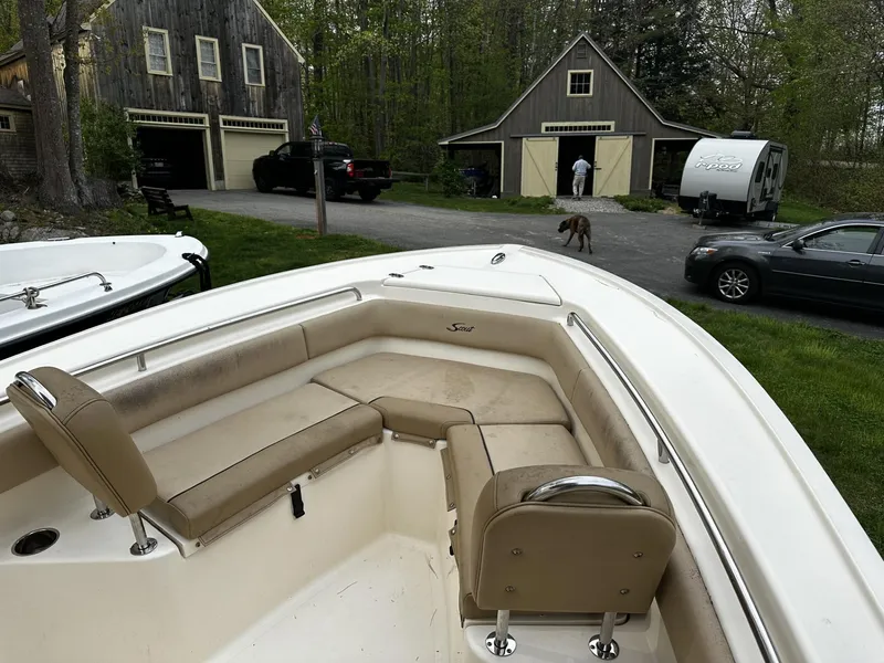 Slide: The Image of 2018 Scout 225 XSF boat parked in a residential driveway with houses and cars. - 5