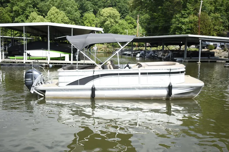 Slide: The Image of 2023 Bennington 22 SXCW pontoon boat docked on a calm lake. - 2