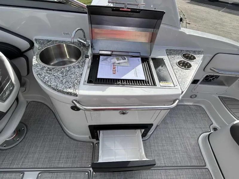 Slide: The Image of 2024 Crownline E280 XS boat kitchen with sink, grill, and storage drawer. - 9
