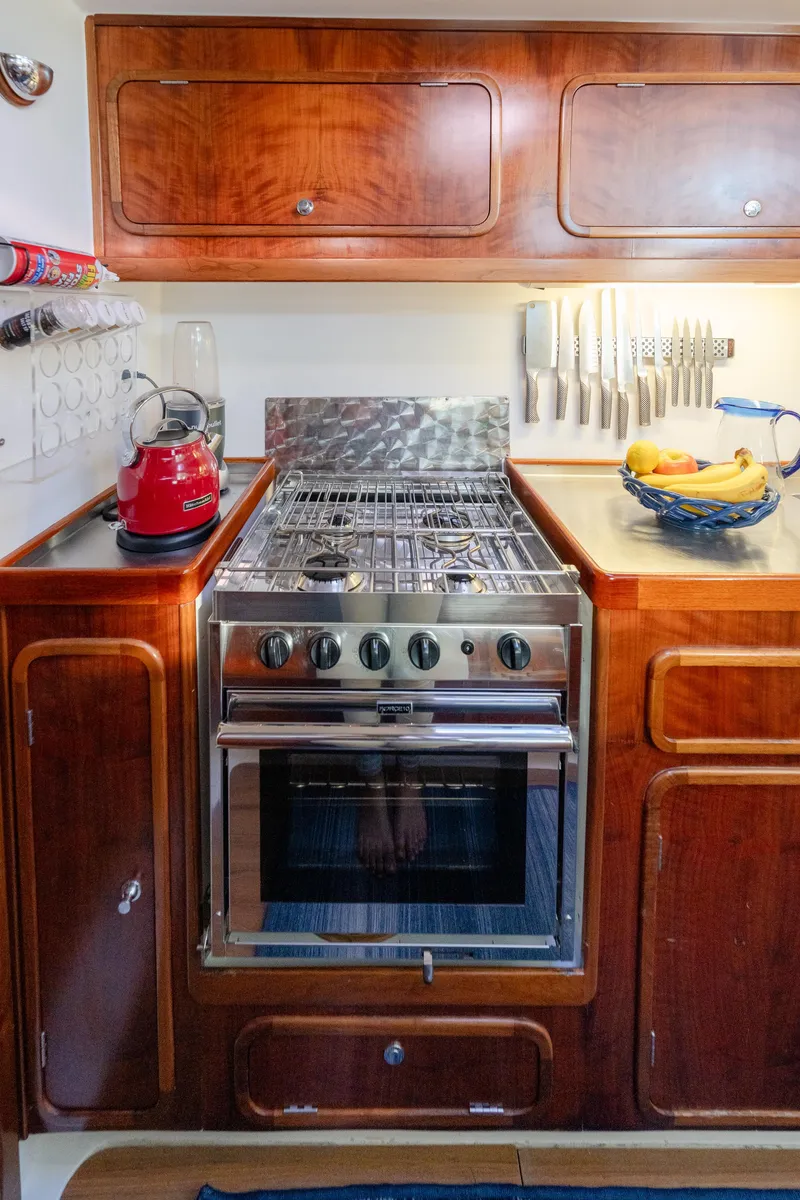 Slide: The Image of Galley kitchen in 2009 Chris White Atlantic 57 yacht with stove and wooden cabinetry. - 13