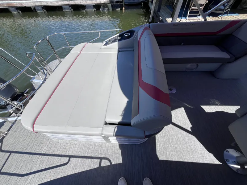Slide: The Image of 2023 Bennington 23 SXSB boat interior with gray and red seating, dockside view. - 7