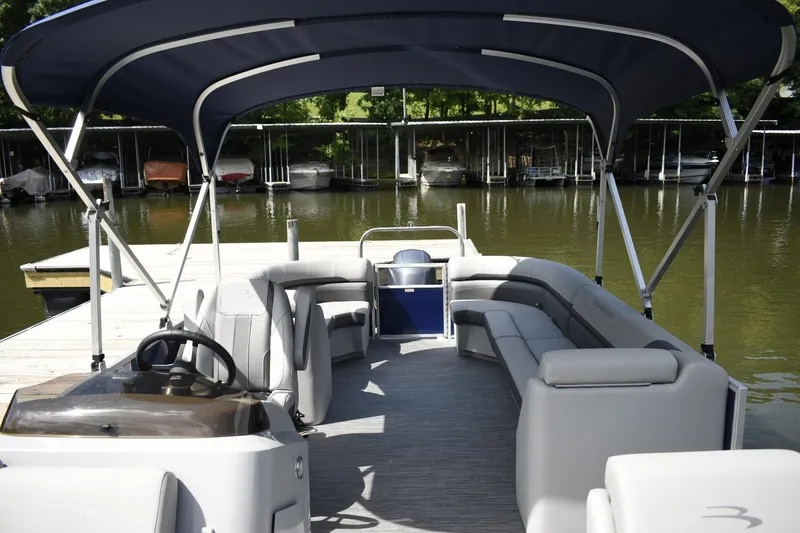 Slide: The Image of 2023 Bennington 23 SXSRC pontoon boat with spacious seating and canopy docked at a marina. - 7