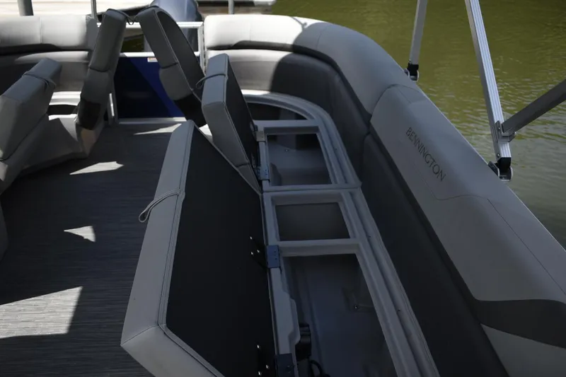 Slide: The Image of 2023 Bennington 23 SXSRC boat with open storage compartments and cushioned seating. - 9